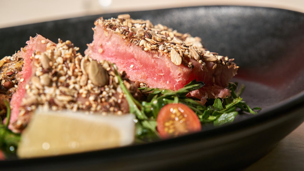 Fresh seared tuna with seed crust, on a bed of greens and cherry tomatoes.
