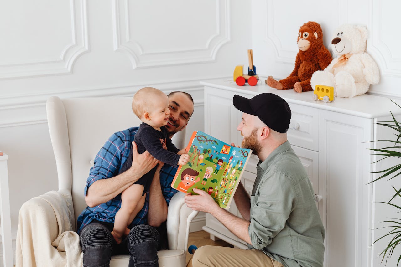 A happy family moment with two dads bonding with their baby indoors.